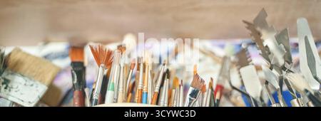 Assortiment de divers outils d'art, y compris des pinceaux et des couteaux à palette dans l'atelier créatif. Banque D'Images