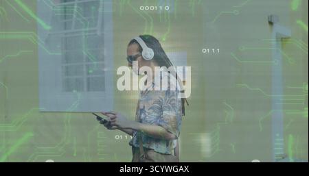 Homme marchant sur la rue devant le mur portant chemise florale, écouteurs, sac de transport sous les circuits. Urbain, technologie, innovation, style de vie, moderne, conn Banque D'Images