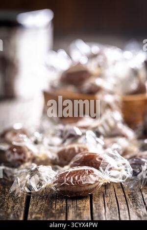 Bonbons sucrés enveloppés dans du papier d'aluminium sur une table en bois. Banque D'Images