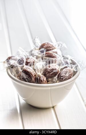 Bonbons sucrés enveloppés dans du papier d'aluminium sur une table blanche. Banque D'Images
