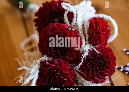 Un magnifique gros plan d'un bouquet de mariée avec des dahlias Bordeaux profonds agencés avec art et délicatement enveloppés d'un ruban blanc fluide. parfait Banque D'Images