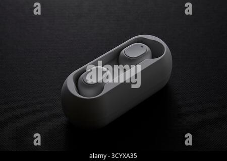 Photo minimaliste du produit d'un étui d'écouteurs blanc sur une surface noire représentant un appareil audio personnel, une technologie moderne portable et un style de vie numérique AC Banque D'Images