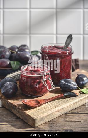 Confiture de prunes dans des bocaux en verre avec des prunes mûres sur un fond clair Banque D'Images