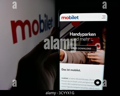 Dans cette illustration photo, une personne tient un smartphone avec la page Web de la société allemande d'applications de mobilité Mobilet sur l'écran devant le logo. Banque D'Images