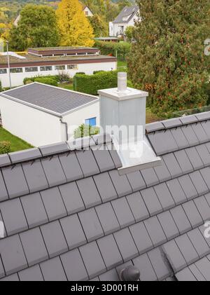 Cheminée avec revêtement métallique sur toit anthracite, vue sur le quartier résidentiel, rénovation de maison, rénovation climatique, Metzingen, Allemagne Banque D'Images
