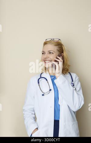 Beau docteur parlant au téléphone à fond vide Banque D'Images