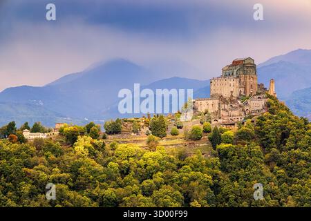 Un sentier de montagne pittoresque serpente à travers la verdure luxuriante des Alpes piémontaises, avec vue sur l'imposante Sacra di San Michele, qui se dresse ma Banque D'Images