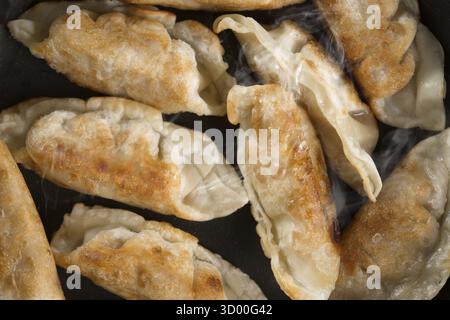 Fermez la cuisson de boulettes frites dans une poêle. Plat chinois avec des vapeurs chaudes, sur fond rustique en bois vintage Banque D'Images