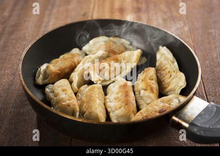 Fermez la cuisson de boulettes frites dans une poêle. Cuisine chinoise avec des vapeurs chaudes, sur fond rustique en bois vintage Banque D'Images