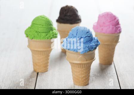 Myrtille, matcha, chocolat et crème glacée à la fraise dans le cône sur fond blanc en bois rustique Banque D'Images