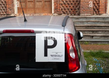 Cremona, Italie -2 octobre 2025 arrière du hayon argenté affichant une grande plaque P rouge pour conducteur provisoire, garé par un bâtiment en brique avec des marches dedans Banque D'Images