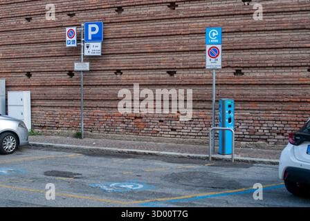 Cremona, Italie -2 octobre 2025 borne de recharge bleue pour véhicule électrique debout dans une place de stationnement désignée avec des symboles d'accessibilité et un panneau de signalisation Banque D'Images