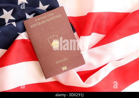 Passeport slovène sur grand drapeau agitant des États-Unis d'Amérique close up. Visa AMÉRICAIN et concept d'immigration Banque D'Images