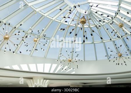 Un intérieur lumineux présente un design de plafond moderne avec un dôme en verre. Élégants lustres en étoile suspendus d'en haut, créant un effet visuel époustouflant Banque D'Images