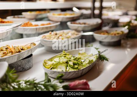 Une variété de salades fraîches et de plats d'accompagnement sont magnifiquement disposés dans des bols de service en marbre lors d'un buffet. Les clients peuvent choisir parmi des légumes colorés et Banque D'Images