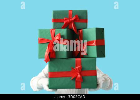 Femme tenant la pile de cadeaux de Noël sur fond bleu Banque D'Images