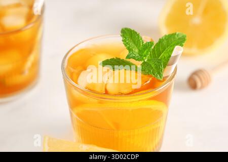 Verre de thé aux fruits avec des feuilles de citron et de menthe sur fond clair Banque D'Images