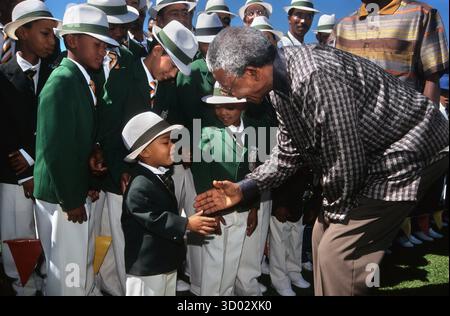 Cape Town Afrique du Sud. Le président Nelson Mandela accueille un jeune membre d'une bande traditionnelle du Cap Minstrel, à Athone. 03/98 Banque D'Images