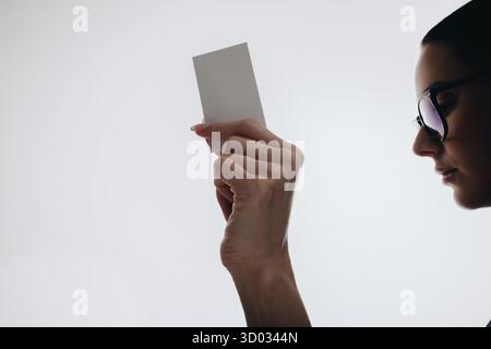 Gros plan d'une personne tenant une carte de visite, mettant en valeur un style abstrait et professionnel. L'image présente un arrière-plan simple, mettant l'accent sur Banque D'Images