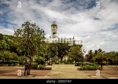 Zanzibar, Tanzanie, République-Unie 27 mars 2018 : la tour de l'horloge est haute au milieu des arbres dans un cadre de parc urbain dynamique. Banque D'Images