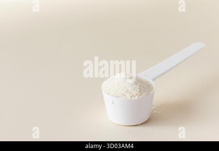 Une cuillère avec de la poudre de collagène hydrolysé sur un fond beige. Le concept d'additifs alimentaires, sain. Banque D'Images