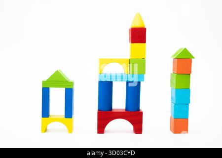 Blocs de bois aux couleurs vives empilés en trois formes uniques sur un fond blanc, représentant la créativité et l'apprentissage. Banque D'Images