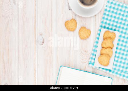Café, biscuits en forme de coeur et le bloc-notes sur la table en bois blanc, avec copie espace Banque D'Images