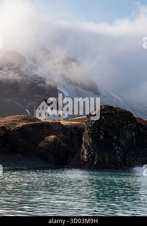 Belle maison solitaire au petit village de pêcheurs d'Arnarstapi et stapafell, falaise volcanique couverte de neige à snaefellsnes péninsule en Islande Banque D'Images
