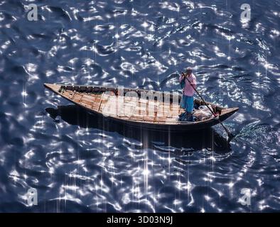 Un homme sur un bateau conduisant un bateau-taxi attend les passagers sur la rivière Buriganga à Dhaka, au Bangladesh, un matin avec l'eau scintillante de la rivière Banque D'Images