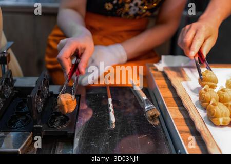 Formes faites de pâte à pâtisserie sur papier cuisson - préparation de biscuits de Noël Linzer. mains féminines méconnaissables avec une pince à épiler transférant des biscuits frais Banque D'Images