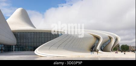 Bakou, Azerbaïdjan - 7 mai 2024 : Centre Heydar Aliyev. Architecture moderne emblématique avec des lignes blanches fluides et une façade en verre sous un ciel nuageux. Les gens sur la place Banque D'Images
