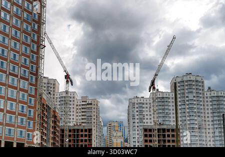 Chantier de construction urbaine avec grues imposantes et bâtiments résidentiels modernes, mettant en valeur le développement dynamique de l'architecture urbaine contre A. Banque D'Images
