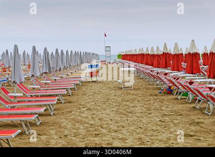 transats et parasols fermés sur une plage vide Banque D'Images