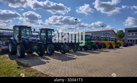 Winsen, Allemagne ; 30 septembre 2025 : gamme de nouveaux tracteurs Farmtrac et Deutz-Fahr stationnés sur le chantier naval de l'importateur sous le ciel bleu, différentes couleurs dont bl Banque D'Images