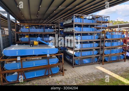 Winsen, Allemagne ; 30 septembre 2025 : caisses en métal avec coupeuses rotatives bleues stockées sous le toit dans la cour d'importation de machines agricoles, montrant compact Banque D'Images