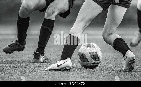 Gros plan de deux joueurs de football en compétition pour le ballon pendant un match. Banque D'Images