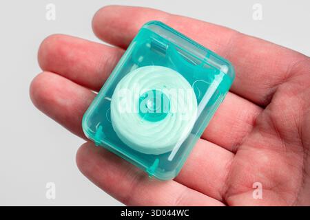 Fil dentaire dans un étui en plastique vert sur la paume de la main. Produits d'hygiène buccale Banque D'Images