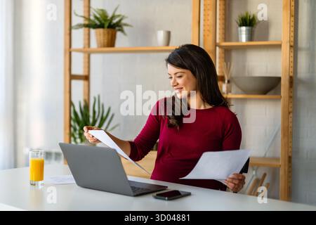 Femme d'affaires professionnelle heureuse réussie travaillant sur son ordinateur portable dans un bureau à domicile lumineux Banque D'Images