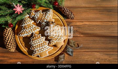 Biscuits de Noël en pain d'épices sur plateau en bois. Biscuits en pain d'épice décorés en forme de sapin de Noël avec glaçage blanc sur un rond Banque D'Images