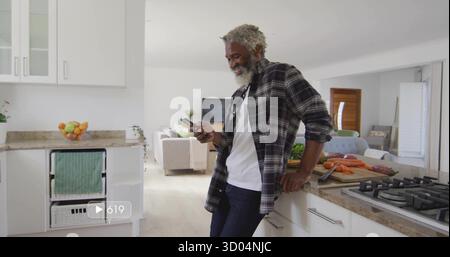 Homme penché portant chemise à carreaux vérifiant smartphone dans la cuisine moderne, avec des carottes, espace copie Banque D'Images