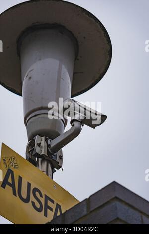 Gros plan d'une caméra de sécurité montée sur un poteau sous un ciel couvert Banque D'Images