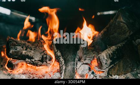 Un feu brûlant dans une cheminée, avec les flammes atteignant le plafond. Le feu est entouré de bûches, et les bûches brûlent brillamment, créant Banque D'Images