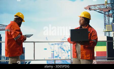 Travailleur de plate-forme offshore supervisant les activités de pont et vérifiant la conformité de sécurité à l'aide d'un ordinateur portable. L'employé effectue la maintenance de routine sur l'engin de forage de production d'énergie, Banque D'Images