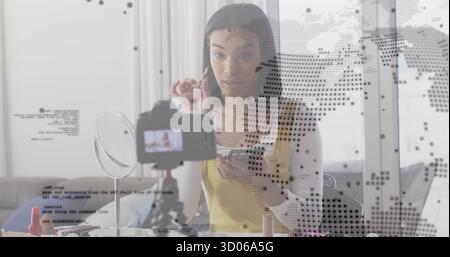 Application de maquillage vlogger se filmant elle-même à la table du salon, avec brosse miroir trépied smartphone Banque D'Images