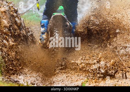 enduro roule à travers la boue avec de grandes éclaboussures, conducteur éclaboussant de la boue sur un terrain humide et boueux, Motocross coureur dans un terrain humide et boueux couvrant la dri Banque D'Images