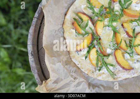 Pizza très savoureuse et intéressante à la pêche et au bleu de la botte avec arugula sur parchemin. Délicieux, goût intéressant de pizza aux fruits. Pizza grillée, outdoo Banque D'Images