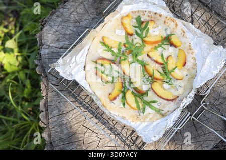Pizza très savoureuse et intéressante avec pêche et bleu ou avec arugula. Délicieux, goût intéressant de pizza aux fruits. Pizza grillée, activités de plein air Banque D'Images