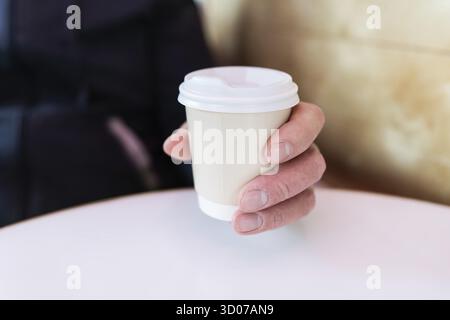 Tasse de café en papier dans une main masculine. Café à emporter. Marche en plein air Banque D'Images