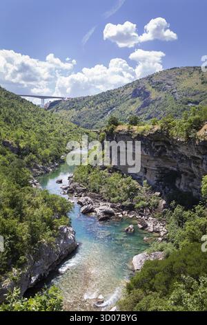 Une rivière sereine coule à travers un canyon spectaculaire, entouré d'une végétation luxuriante et d'imposantes falaises rocheuses Banque D'Images