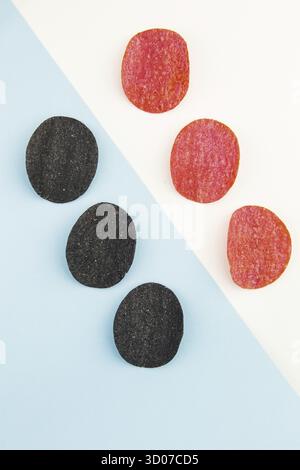 Chips de pommes de terre rouges et noires avec sel, piment. Mise en plan isométrique. Fond de puce sur fond blanc et bleu Banque D'Images